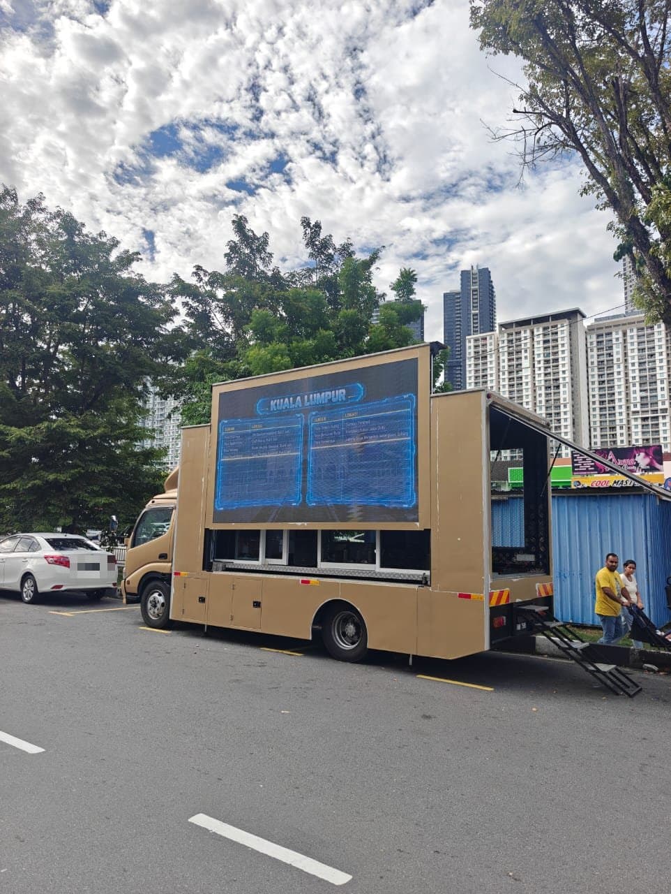 17-ft LED truck parked at the kerb, its screen showing an event schedule
